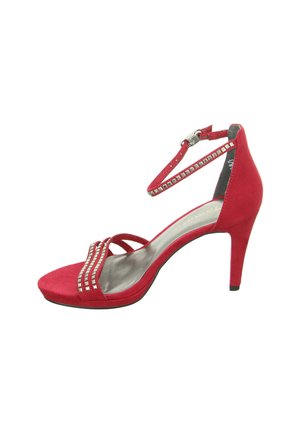 Rote Wildleder-Pumps mit Knöchelriemen, dekorativen Metallnieten und offenem Zehendesign. Leicht geschwungener Absatz.