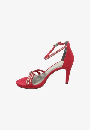 Red suede high heel shoe with an ankle strap, featuring decorative metal studs and an open toe design. Slightly curved heel.
