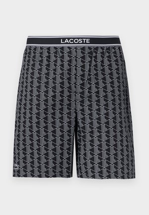 Fekete rövidnadrág geometrikus fehér vonalmintával, rugalmas derékpánttal, amelyen fehér "LACOSTE" logó található, valamint kis krokodil emblémával az alján.