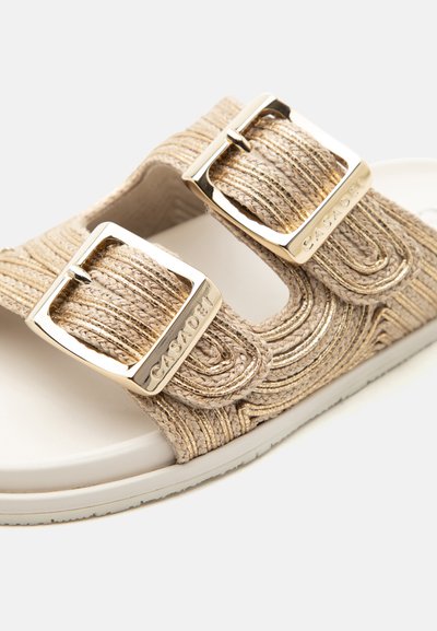Sandale beige avec deux brides en tissu texturé et boucles rectangulaires dorées gravées "CASADEI" sur une semelle blanche.