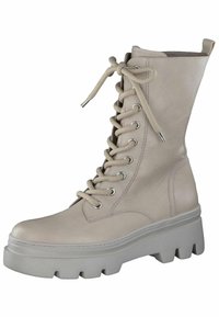 Stivaletto in pelle beige con punta rotonda, alto design con lacci e suola spessa e testurizzata bianca caratterizzata da profonde scanalature.
