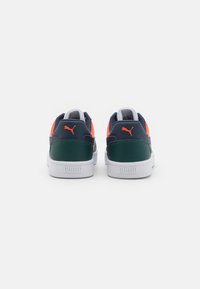 Puma sneakers med en marineblå overdel, grønn hæl og lyse korallfarger, med en hvit gummisåle og teksturerte detaljer på sidene.