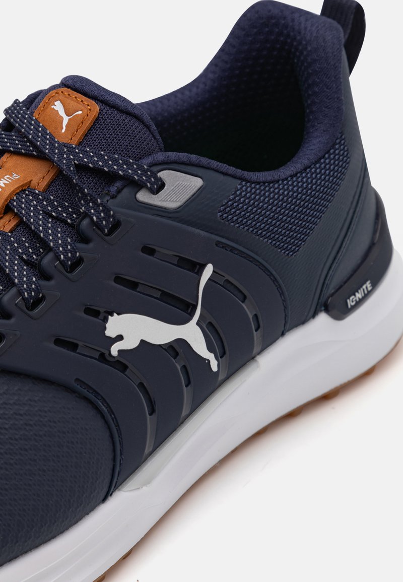 Marineblaue Sportschuh mit Mesh-Obermaterial, silbernem Logo und braunen Akzenten. Verfügt über ein strukturiertes Design mit einer weißen Sohle und atmungsaktivem Material.