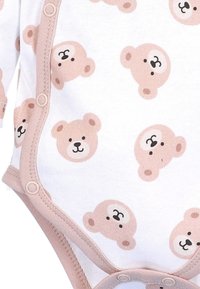 Puuvillane pikakätisel bodysuit, millel on valge taust ja korduvad heleda pruunid karu näod. Kinniseosed jalgade avade ääres.