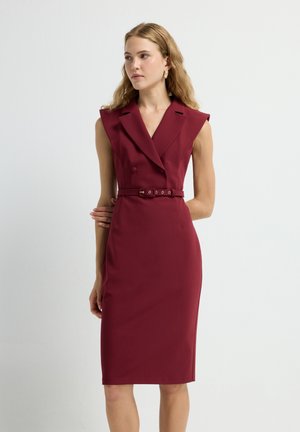 Burgundy tailored dress with a double-breasted design, shoulder pads, and a matching belted waist. Smooth fabric with a sleek silhouette.
