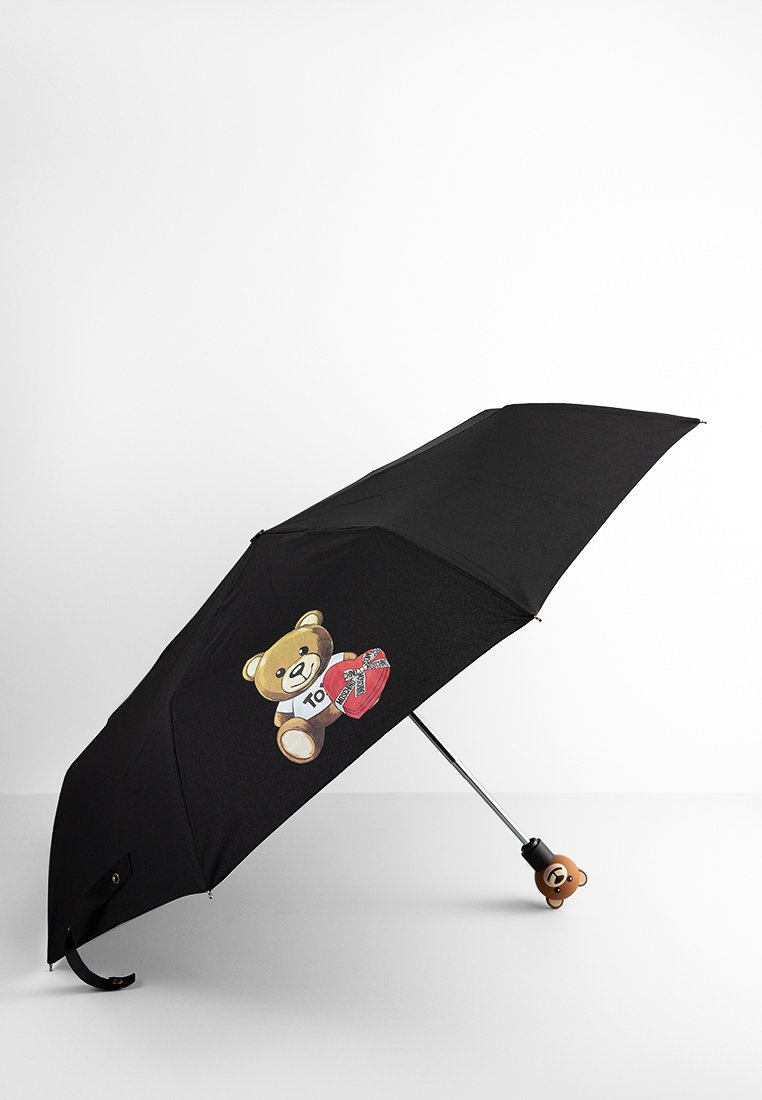 Un parapluie noir avec un ours en peluche tenant un cadeau en forme de cœur sur la toile et une poignée en forme d'ours en peluche.
