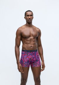 Rugalmas anyagból készült boxer alsó, színes virágos paisley mintával rózsaszín és kék színben, fekete derékpánttal, amelyen a "BJÖRN BORG" felirat szerepel.