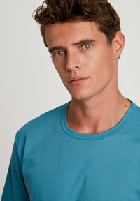 Blauwe T-shirt met korte mouwen, gemaakt van een gladde stof, met een ronde hals en een relaxte pasvorm. Het oppervlak heeft een subtiele textuur.