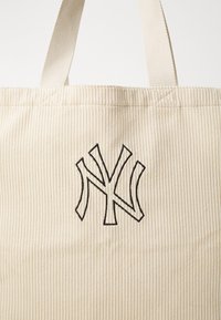 Beige τσάντα tote από κοτλέ με χοντρές νάιλον ιμάντες, με μαύρο κεντητό λογότυπο NY στο μπροστινό μέρος και ριμπé υφή σε όλη την επιφάνεια.