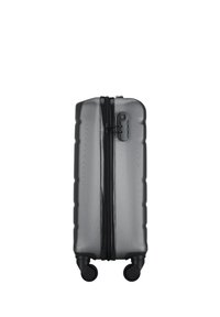 Hard-shell suitcase with a gray textured exterior, vertical ribbed design, double zipper, and four black wheels for mobility.