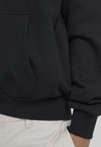 Mörkblå hoodie av mjuk bomullsblandning; har en framficka, ribbade ärmslut och nederkant samt en slät, strukturerad tyg.