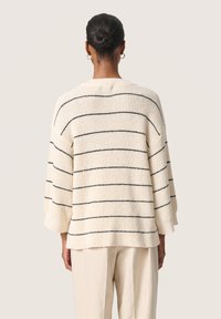 Cremefarvet sweater med marineblå striber, ribbet tekstur, drop shoulders og trekvartlange ærmer. Udført med en rund halsudskæring.