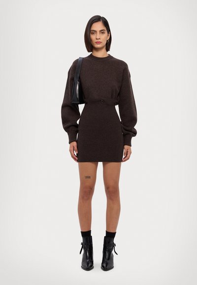 Brun strikket kjole med pufærmer, en tætsiddende talje og knapper. Sorte ankelstøvler med spidse tæer. Kort længde, glat tekstur.