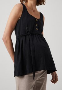 Top noir sans manches avec un col rond, trois boutons dorés et une ceinture à nouer à la taille. Fabriqué à partir d'un tissu doux avec un design ample et fluide.