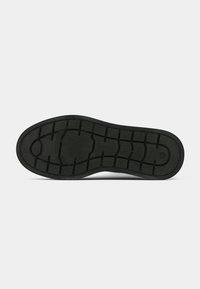 Semelle de chaussure noire avec un motif de semelle géométrique, présentant un bout et un talon arrondis, affichée sur un fond blanc.