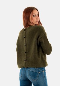 Olivengrøn strikket sweater med en fluffy tekstur, der har en rund halsudskæring og syv sorte knapper ned ad ryggen.