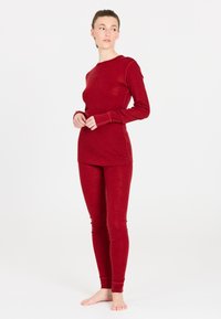 Röd långärmad topp och leggings-set tillverkat av mjukt tyg. Fitted design med ribbad mudd och en jämn textur.