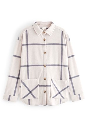 Veste beige boutonnée avec un grand motif à carreaux gris, col pointu, manches longues et deux poches carrées à l'avant.