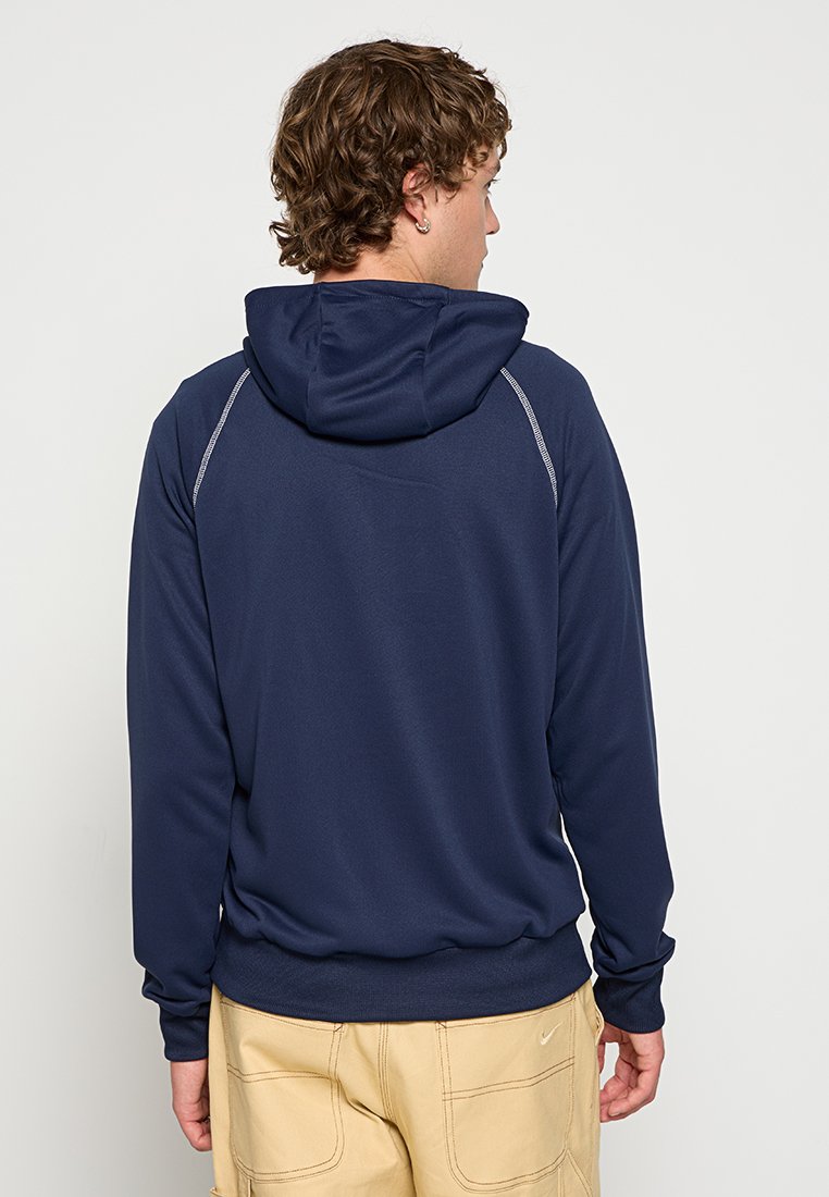 Felpa blu navy con cappuccio e cordino, texture liscia e cuciture decorative grigie. Presenta una tasca a marsupio e polsini aderenti.