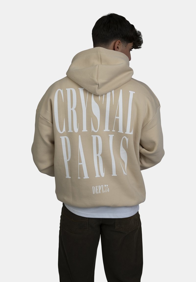 Felpa beige con una grande stampa bianca che recita "CRYSTAL PARIS" sul retro, caratterizzata da una vestibilità comoda e un cappuccio regolabile.