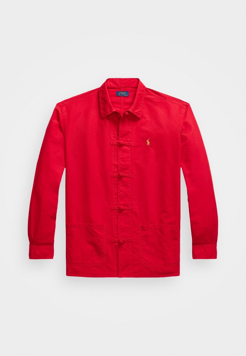 Giacca di cotone rossa con maniche lunghe, chiusura frontale con bottoni, due tasche anteriori e un piccolo logo ricamato sul lato sinistro del petto.