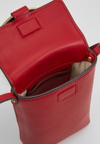 Rød lædertaske med en glat tekstur, der har en åben top, indvendige kortholdere og en guldfarvet detalje. Foret med et sildebensmønster.