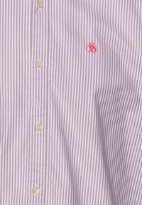 Camicia bianca con sottili righe verticali rosa, bottoni beige lungo il centro e piccolo logo ricamato rosso sul lato destro.