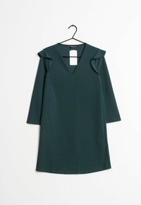 Vestido verde oscuro con escote en forma de V, manga larga, acentos de volantes en los hombros y un dobladillo recto que presenta aberturas laterales.