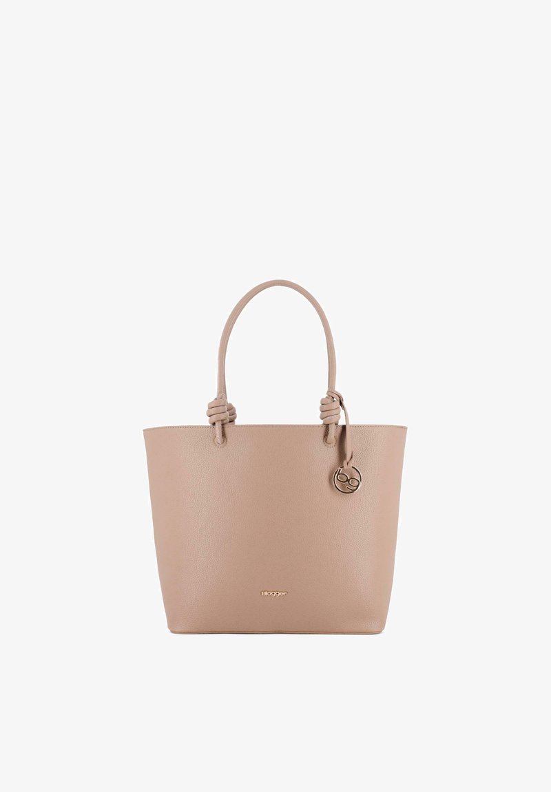 Bolso tote de cuero beige con dos asas anudadas y un colgante redondo dorado colgado en el asa derecha.