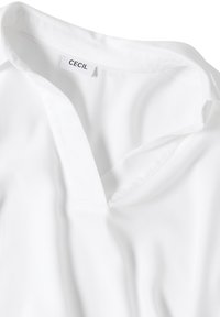 Chemise blanche à col en V avec un col montant et une étiquette de marque "CECIL" cousue à l'intérieur du col, présentée à plat sur un fond blanc.