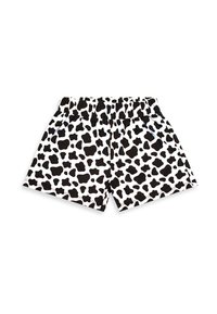 Shorts à taille élastique imprimé vache noir et blanc posés à plat sur un fond blanc.