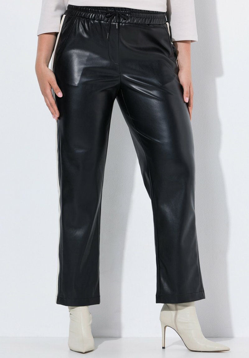 Černé kalhoty z umělé kůže se rovný střih, elastickým pasem a bočními detaily. V kombinaci s krémovými špičatými kotníkovými botami.