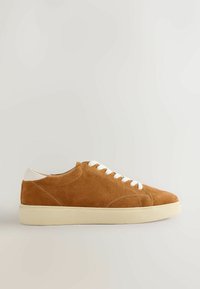 Baskets basses en daim marron avec lacets blancs et semelle couleur crème, vues de profil sur fond neutre.