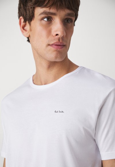 White cotton t-shirt with a crew neckline, featuring a small black "Paul Smith" logo on the left chest. Smooth texture, short sleeves.