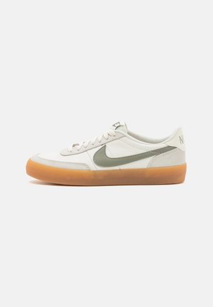 Scarpa Nike sneaker bianca low-top con swoosh grigio e suola in gomma color naturale, vista laterale su sfondo bianco semplice.