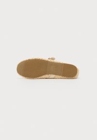 Sandalia de esparto beige con suela de yute trenzado texturizado, tira superior de sintético suave y un diseño de plantilla plana y blanda.