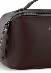 Bruine leren tas met een ronde vorm, met een zilveren rits en zwarte hardware accenten. Subtiele stiksels langs de randen.