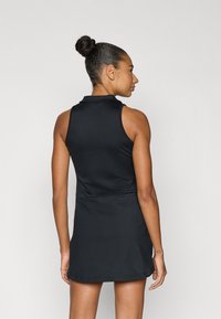 Μαύρο αμάνικο πόλο φόρεμα με εφαρμοστή γραμμή, επίπεδη γιακά και απαλή υφή, που φτάνει μέχρι το μέσο μηρού με ελαφριά φούστα.