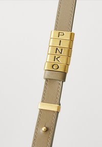 Fivela de cinto em metal dourado com a inscrição "PINKO" em uma tira de couro verde-oliva texturizada, com detalhe de costura e um acabamento de botão redondo.