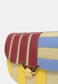 Borsa in paglia intrecciata con dettagli in pelle rossa, blu e gialla e una chiusura dorata. Presenta un design a strisce texturato.