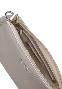 Beige Reißverschlusstäschchen mit glatter Textur und mehreren Fächern; mit silbernem Zubehör und einem geprägten Logo auf der Außenseite.