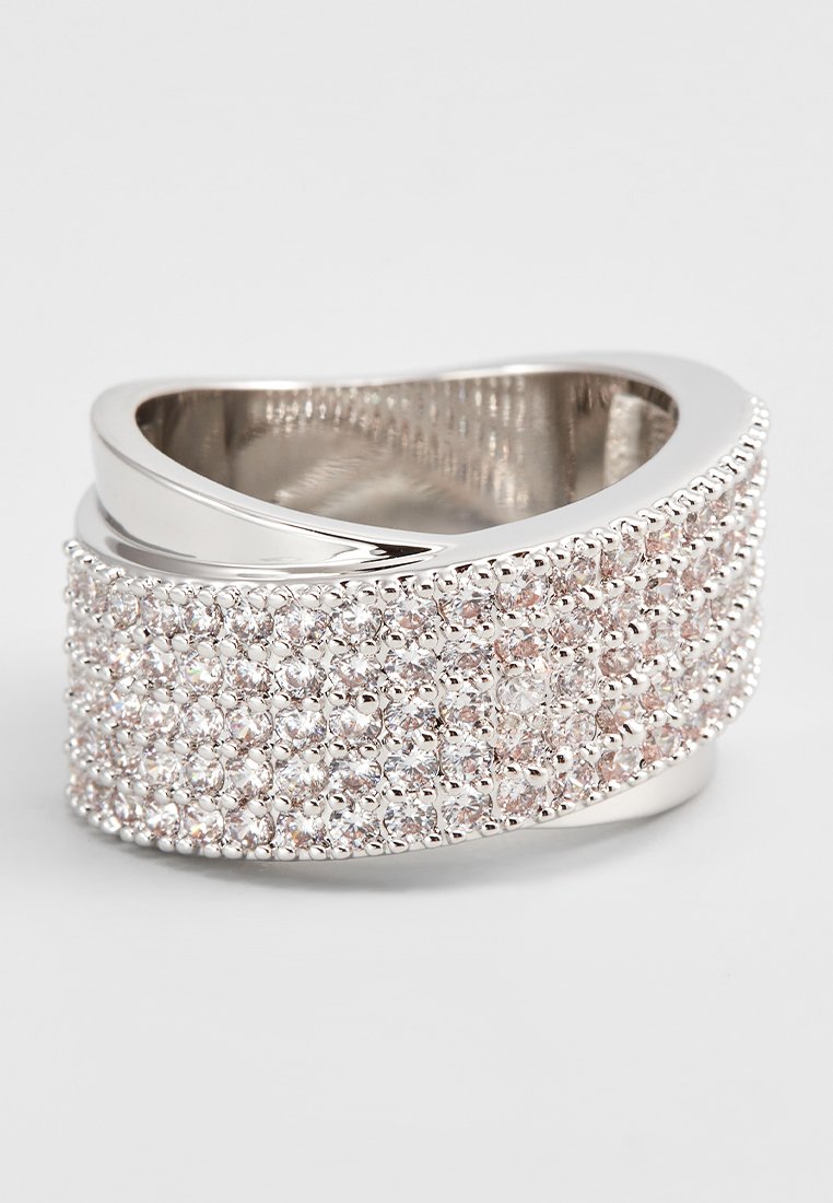 Silberfarbener Ring mit gewelltem Design, verziert mit Reihen von kleinen, klaren und pinken Kristallen, die in einem strukturierten Band eingearbeitet sind.