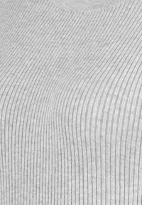 Grauer, gerippter Strickstoff mit vertikalen Linien, verfügt über eine glatte Textur und einen leicht geschwungenen Ausschnitt. Keine sichtbaren Muster oder Akzente.