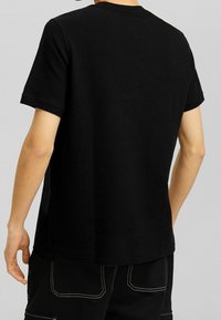 Black short-sleeve t-shirt with a ribbed texture and a crew neckline. Features a relaxed fit and straight hemline.