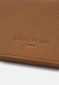 Braune Lederbörse mit strukturierter Oberfläche. Verfügt über das geprägt Logo "LIEBESKIND" und "BERLIN", mit sichtbaren N ähten entlang der Kanten.