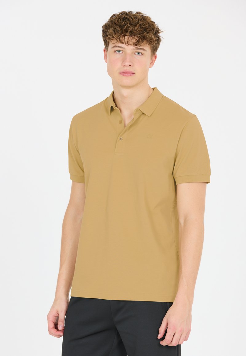 Khaki polo skjorta i mjukt tyg, med klassisk krage, tre-knappars placket och korta ärmar. Diskret logotyp på bröstet.