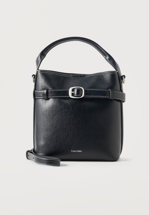 Sac à main en cuir noir Calvin Klein avec poignée supérieure, bandoulière réglable, détail de boucle avant et bords cousus sur fond blanc.