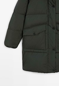 Donkergroen doorgestikte winterjas met grote klepzakken met knopen en zwarte knopen aan de voorkant, met een opgeblazen mouw.