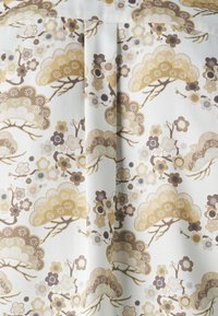 Tela con un patrón de flores y árboles en tonos beige, marrón y crema. Textura suave con detalles decorativos.