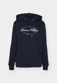 Felpa blu navy con lacci, con stampa logo bianca. Realizzata in tessuto morbido e strutturato. Include una tasca a scomparsa e polsini a coste.